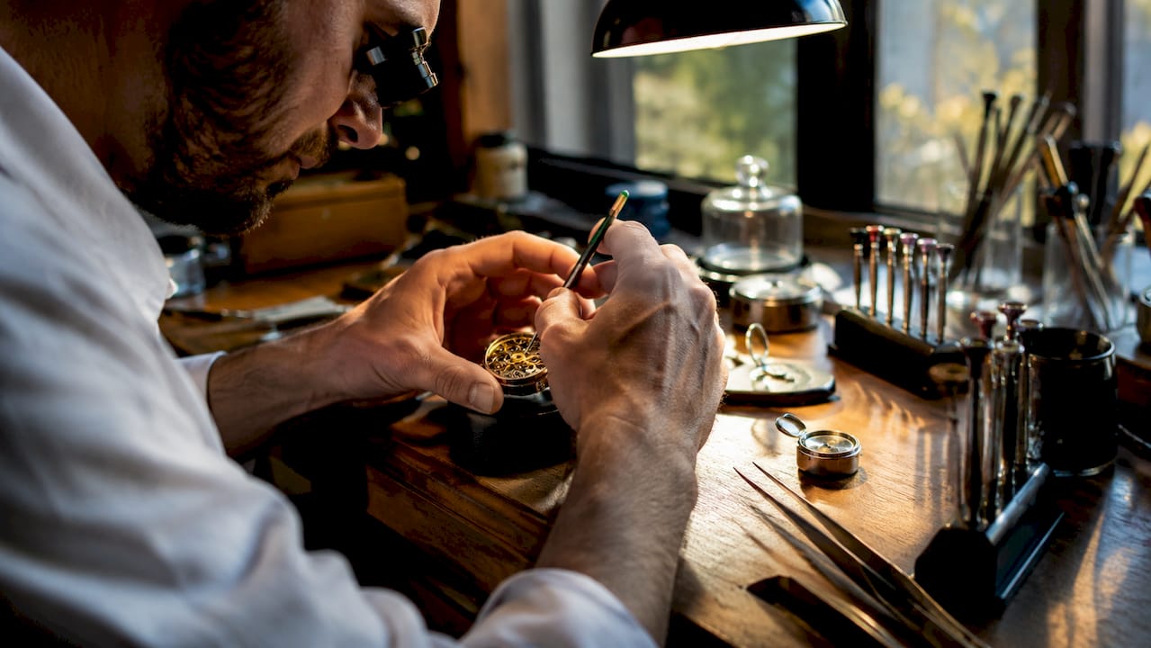 Watchmaker applying lubricant on vintage watch gears
