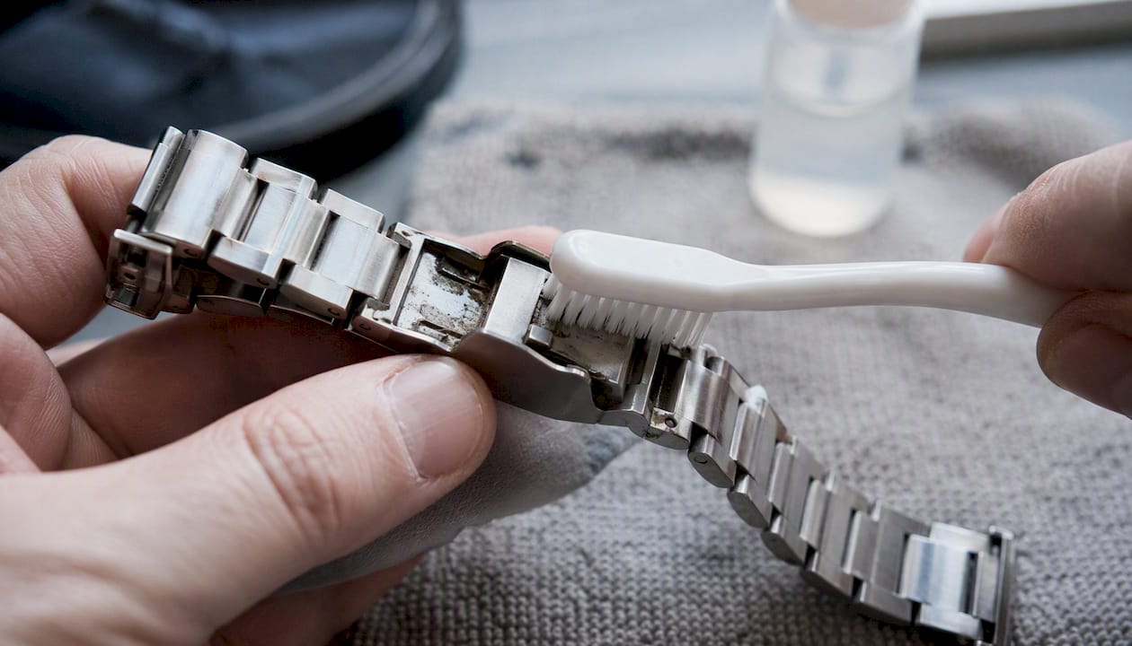 Cleaning debris from watch bracelet gaps with wrapped toothpick