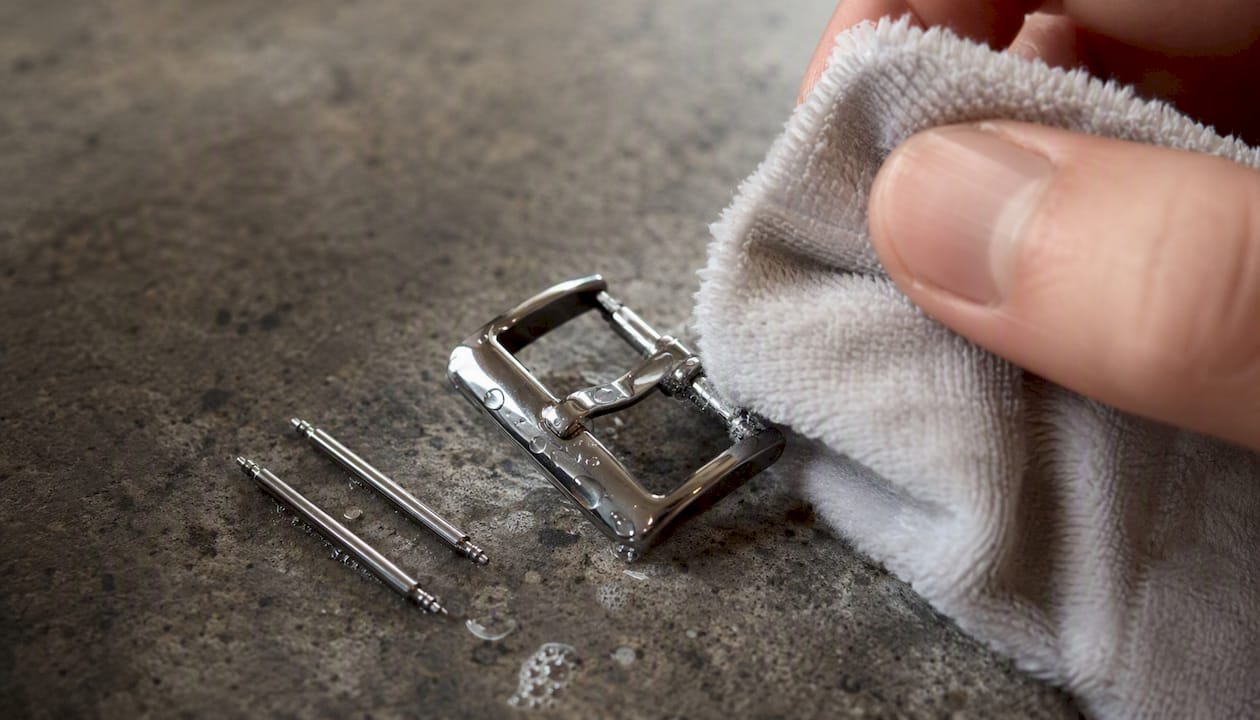 Hand cleaning metal watch buckle with damp cloth