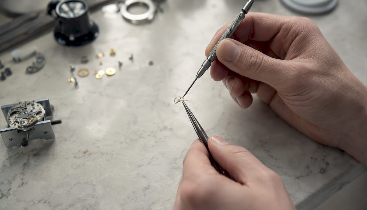 Hands removing watch click spring with tools