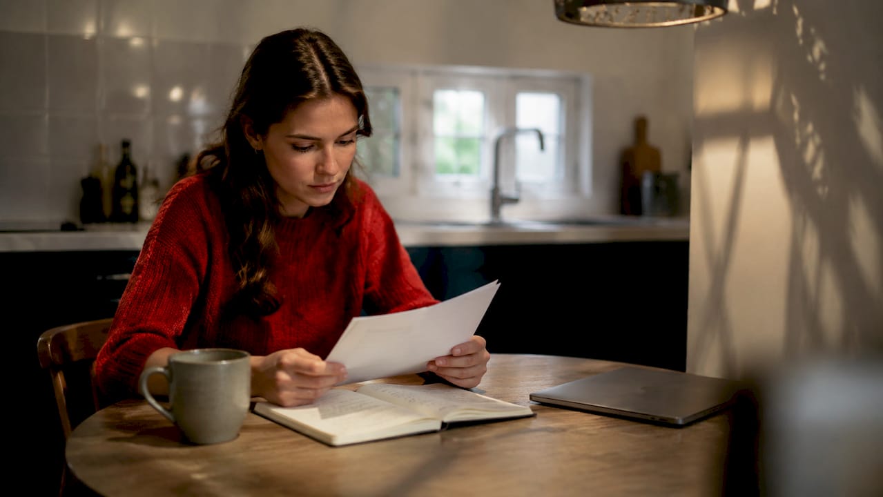 Een expat zit aan de keukentafel en gaat zijn zorgverzekering rustig door.