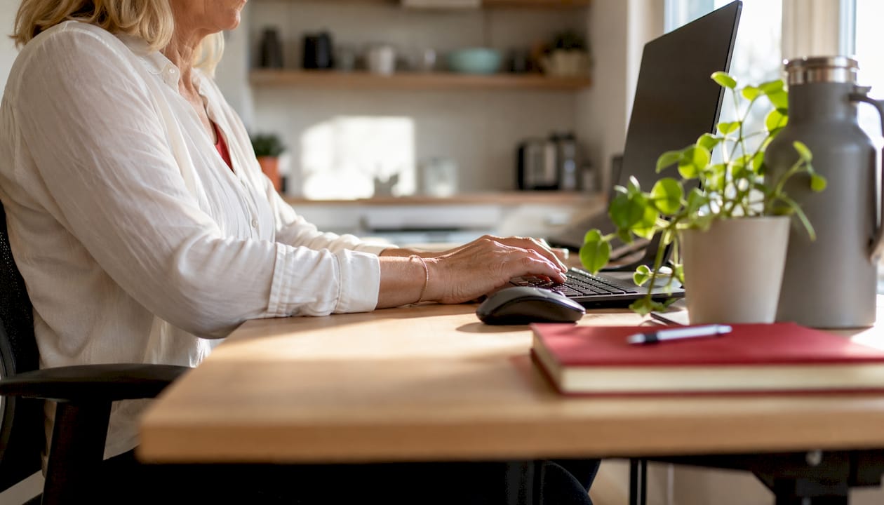 Een vrouw zit comfortabel te werken aan een ergonomisch ingerichte werkplek.