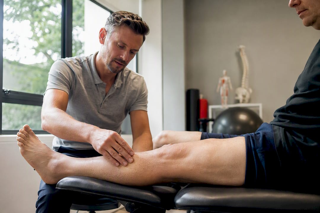 Therapeut die de zwelling in het been van een patiënt onderzoekt