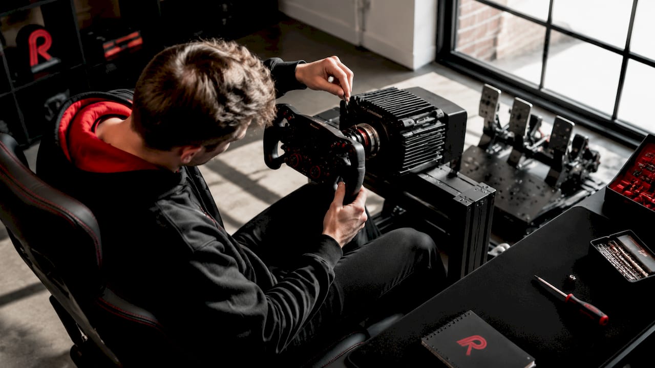 Een simracer stelt het formule-stuur van zijn racesetup nauwkeurig af.