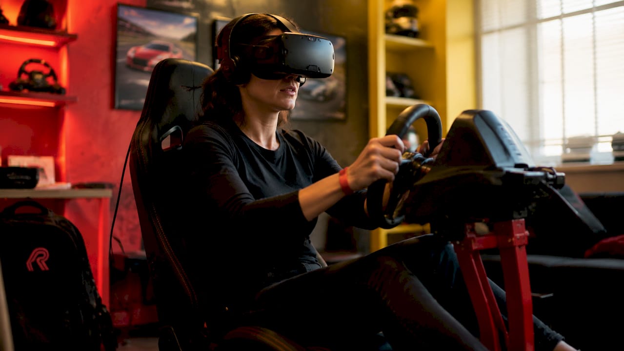 Een vrouw zit volledig geconcentreerd achter het stuur tijdens een virtuele racesimulatie.