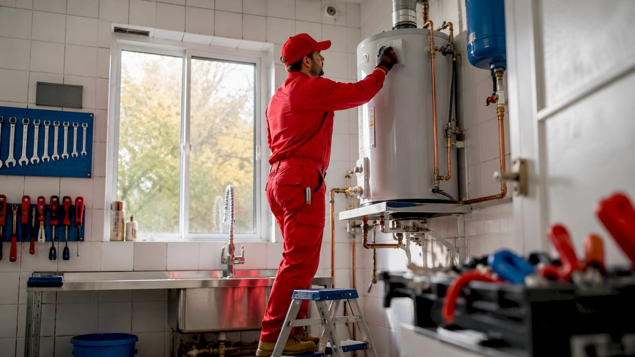 Hands adjusting gas water heater dial