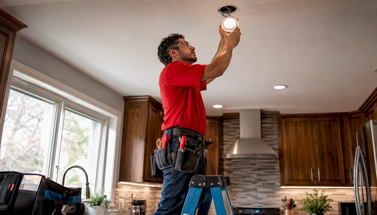 Electrician fits LED panel in office ceiling