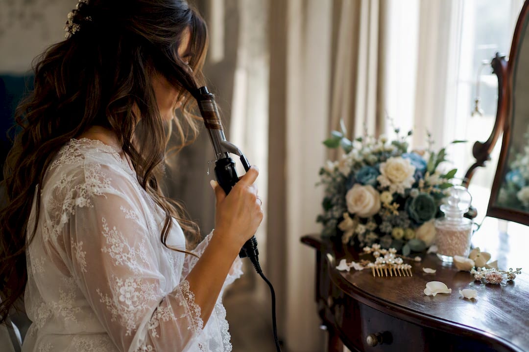 Bride curling hair in warm morning light