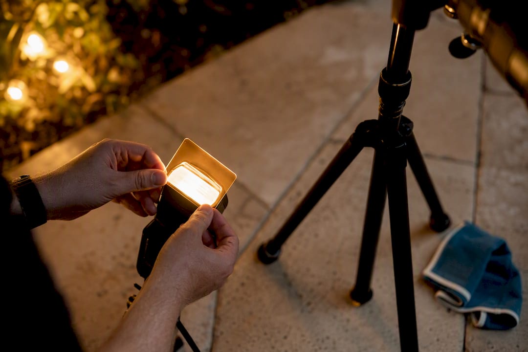Photographer adjusting flash gel beside tripod