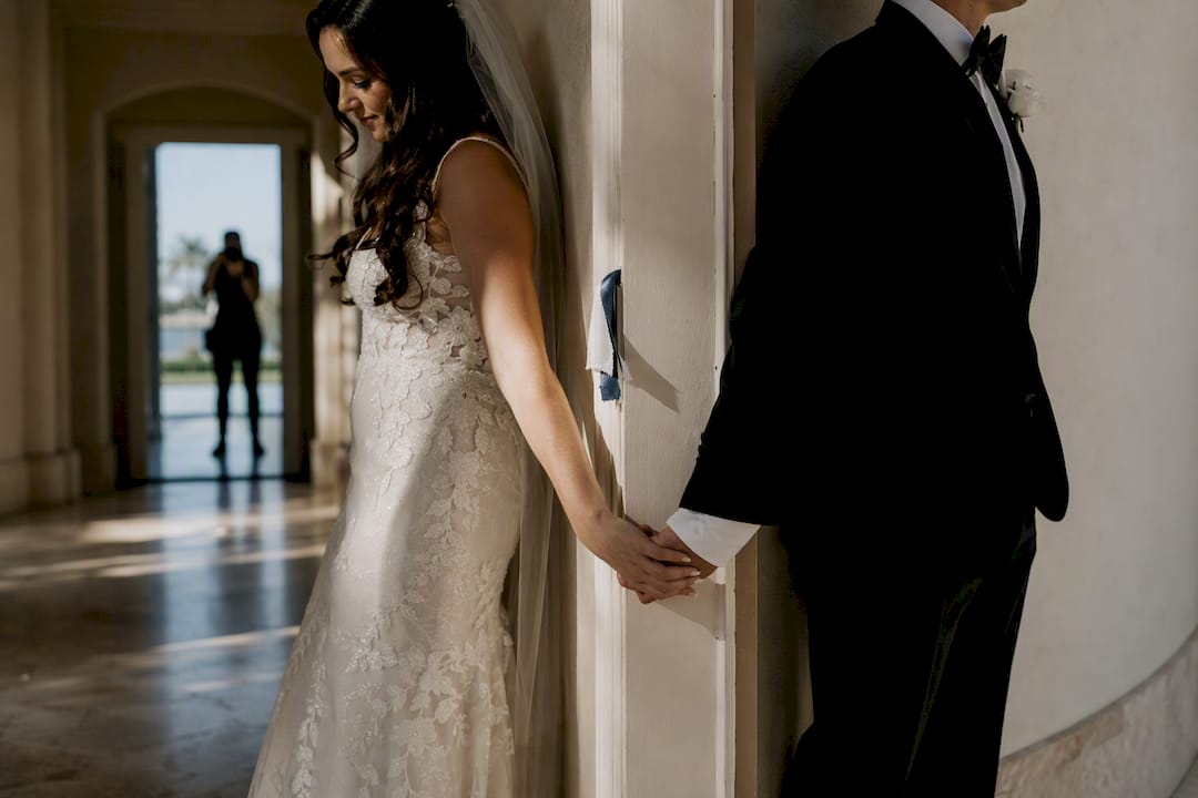 Wedding couple holding hands around doorway