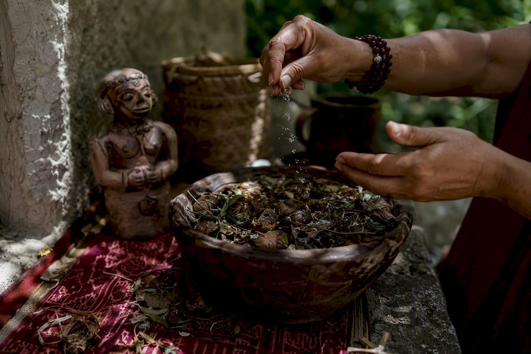 Hands sprinkling salt over ancestral ceremonial bowl