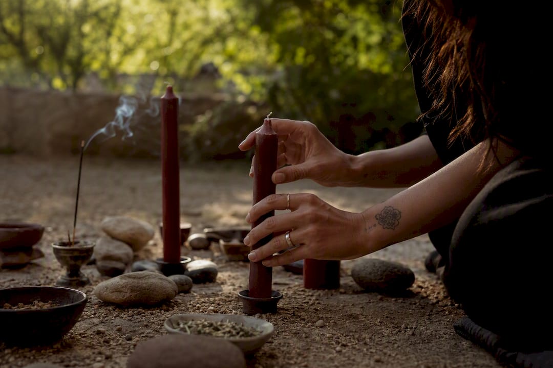 Hands arranging ritual candles on altar