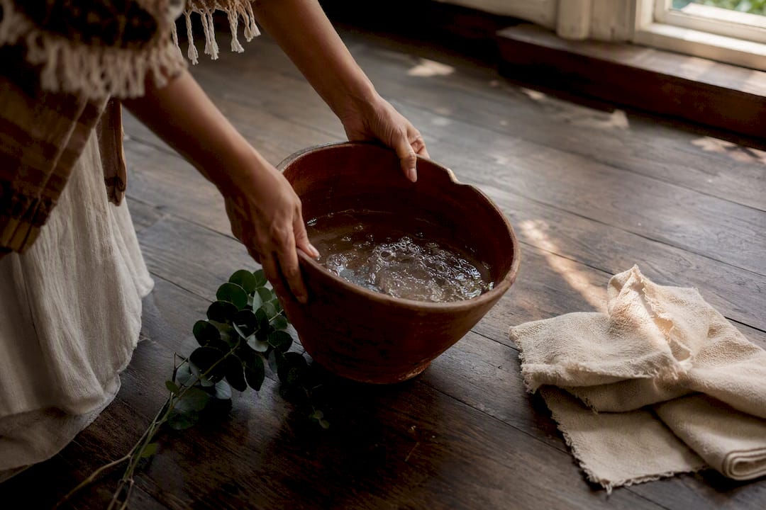 Hands mopping floor with ritual wash bucket