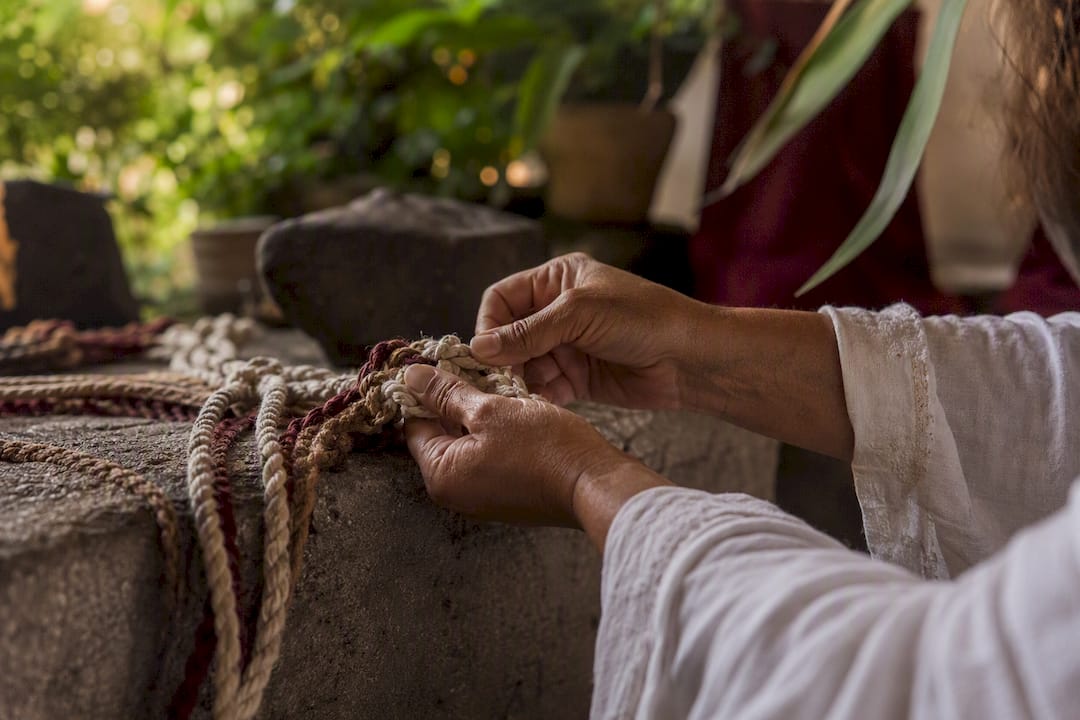 Hands tying knots in braided cord ritual