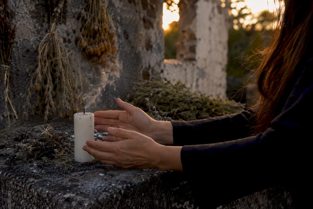 Hands blowing out white candle in ritual