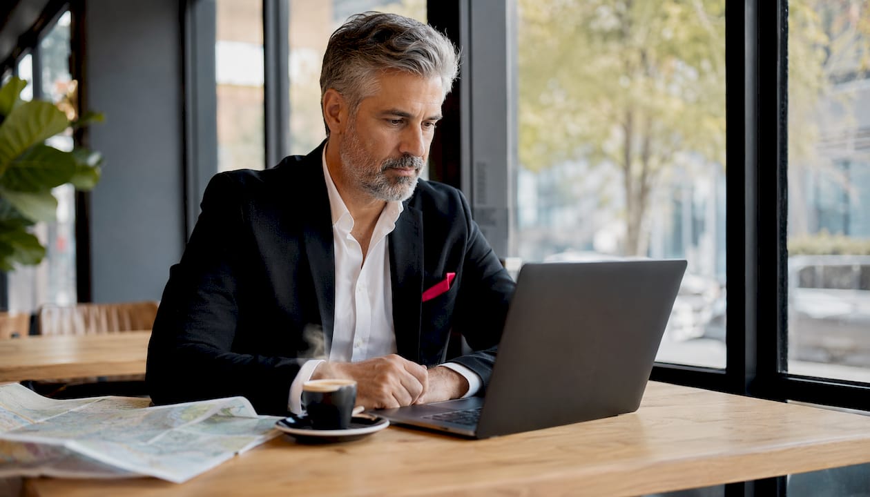 Un hombre revisa opciones de vuelos y hoteles desde su puesto de trabajo en un espacio coworking.