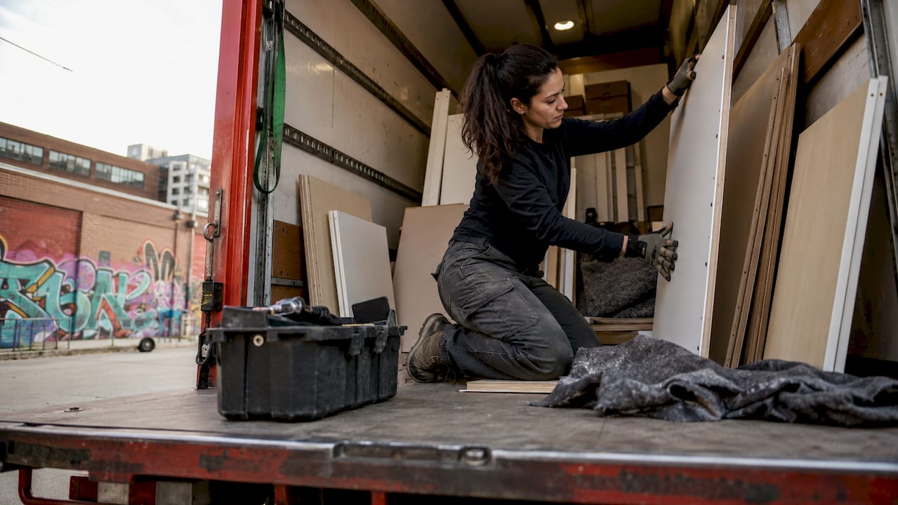 Woman loading flat furniture into freight trailer