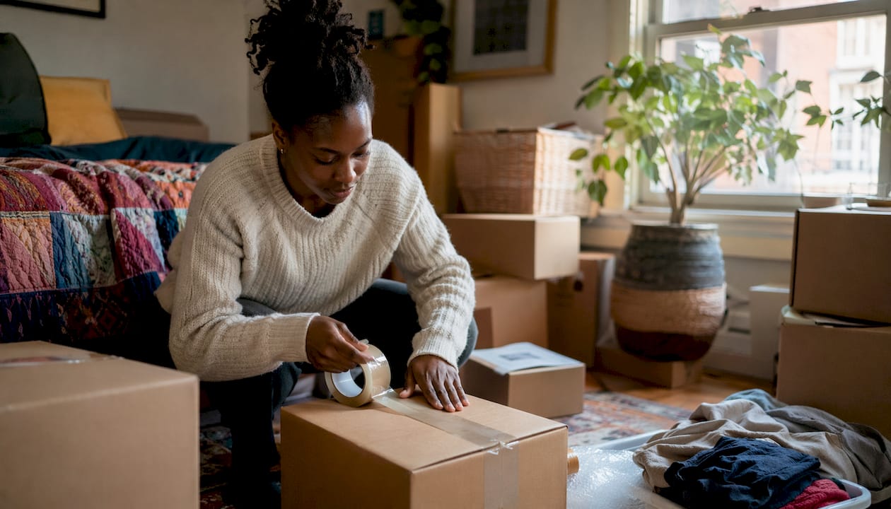 Hands taping moving box in living room