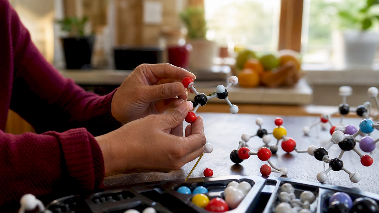 Hands building ester molecular model in lab