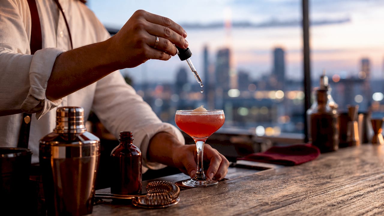 Mixologist adding acid drops to cocktail glass