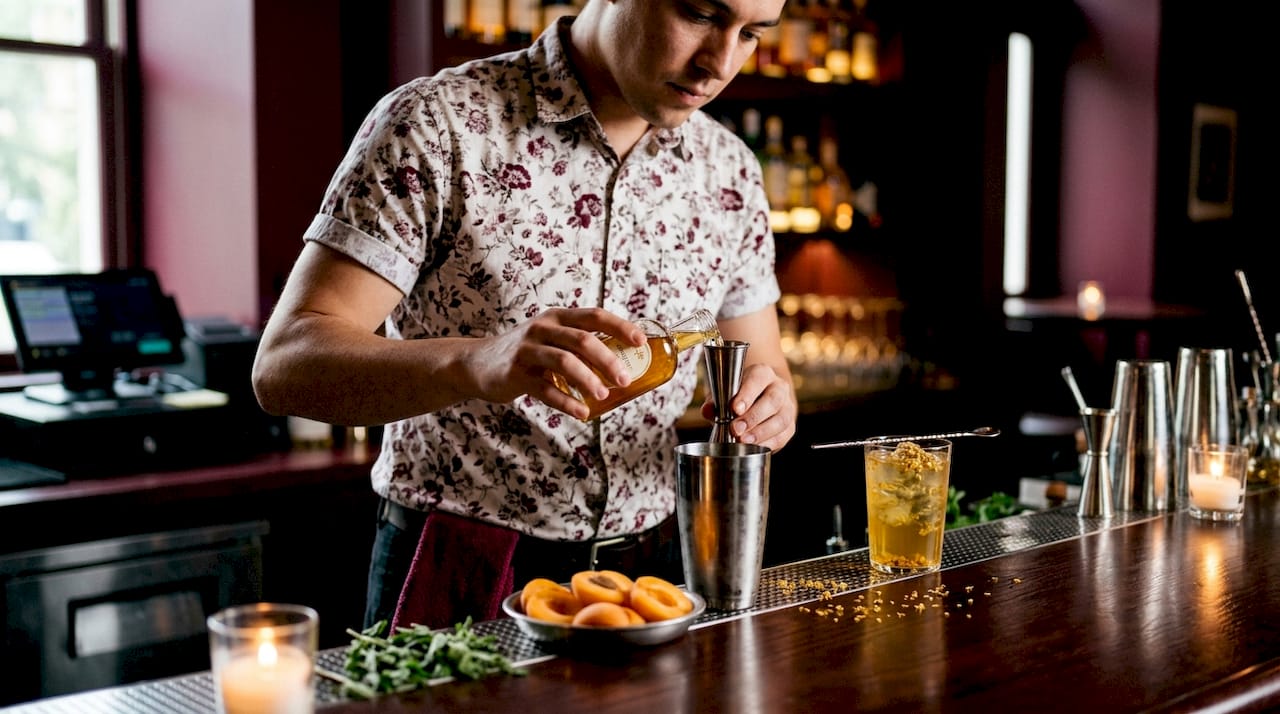Hands mixing osmanthus cocktail at bar