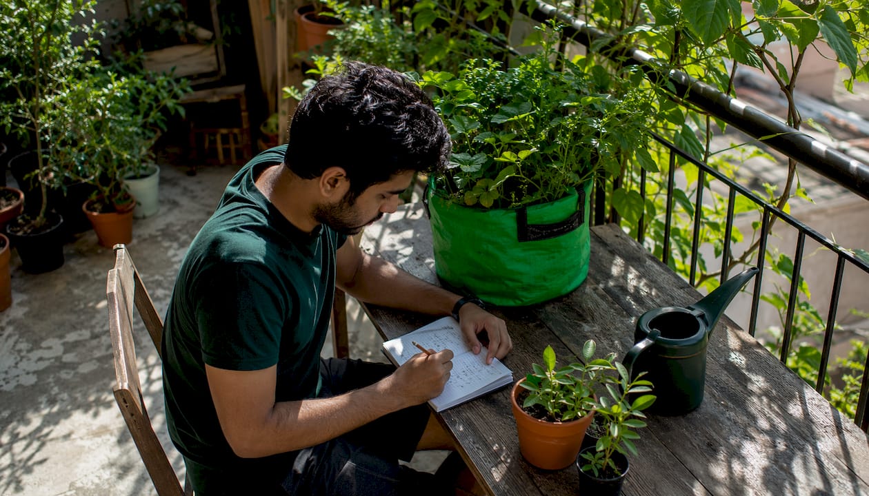 Hands writing sunlight assessment notes on balcony