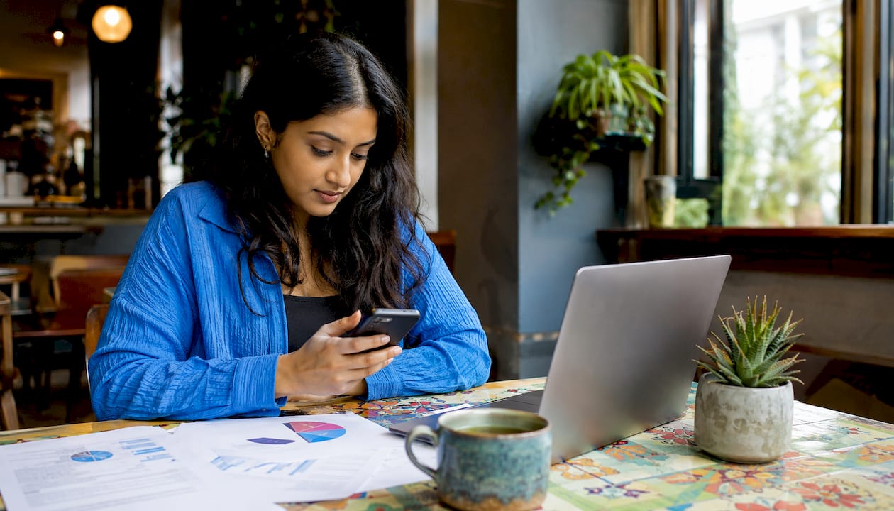 Young woman using smartphone at UK office desk