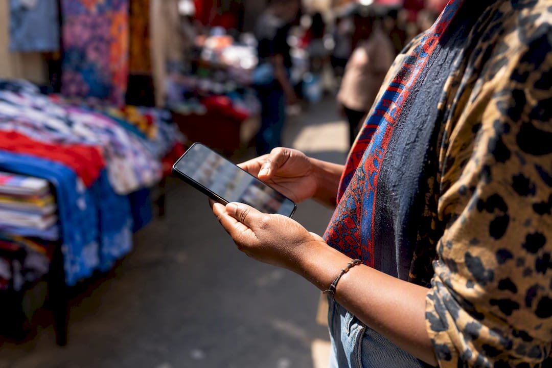 Close-up of retailer holding phone by storefront