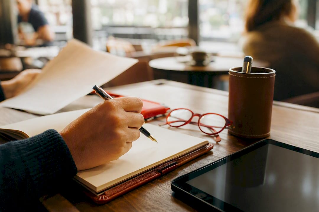 Hand with pen over blank notebook and tablet