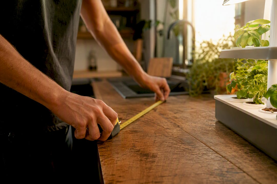 Hands measuring kitchen countertop space