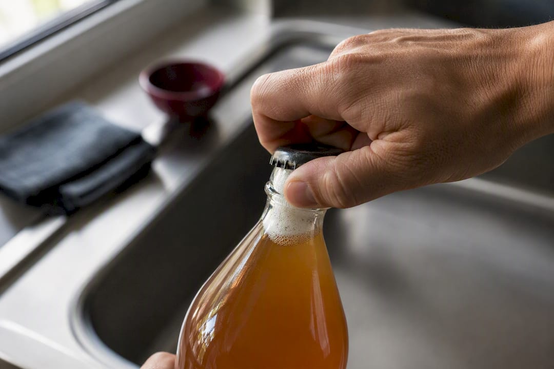 Hand carefully opening pressurized kombucha