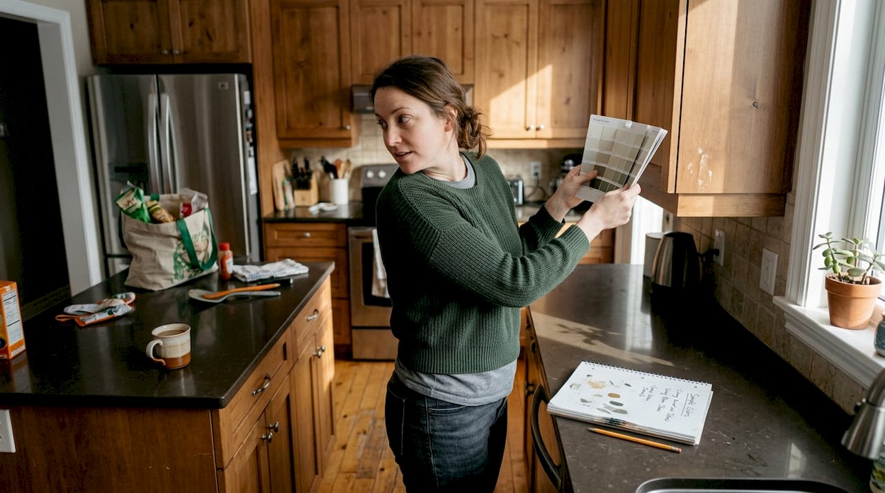 Homeowner comparing color swatch to cabinets