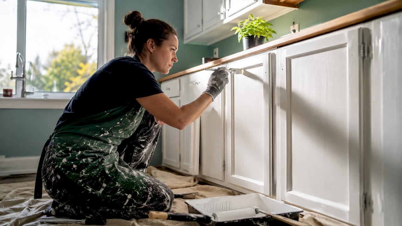 Painter applying enamel on rental kitchen cabinets