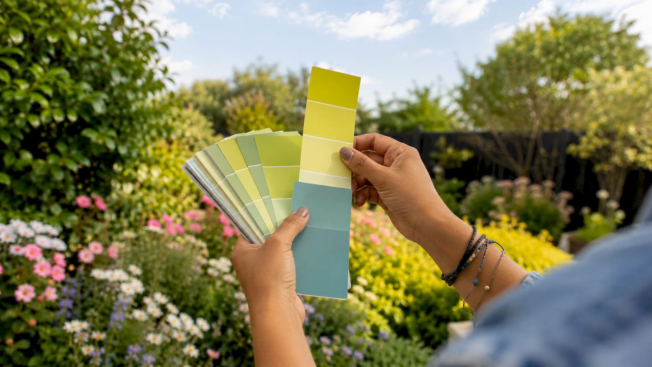 Hand holding paint color swatch cards near window