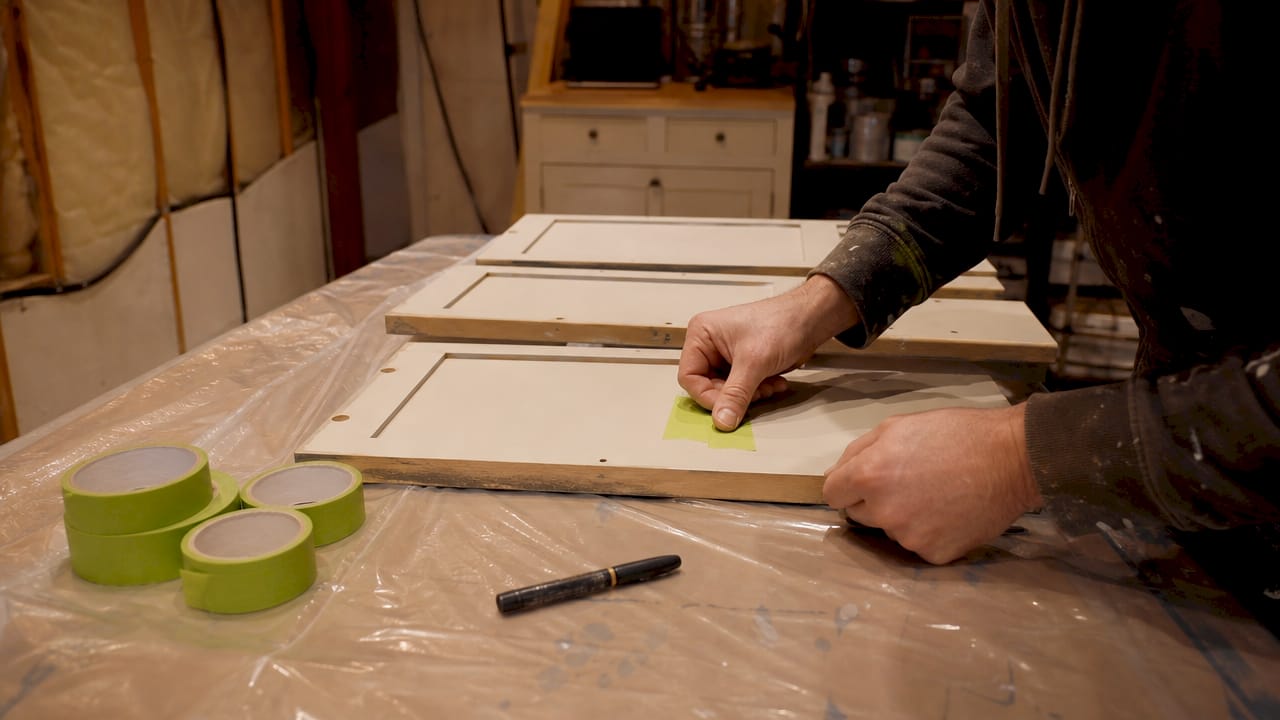 Hands labeling cabinet doors with painter's tape