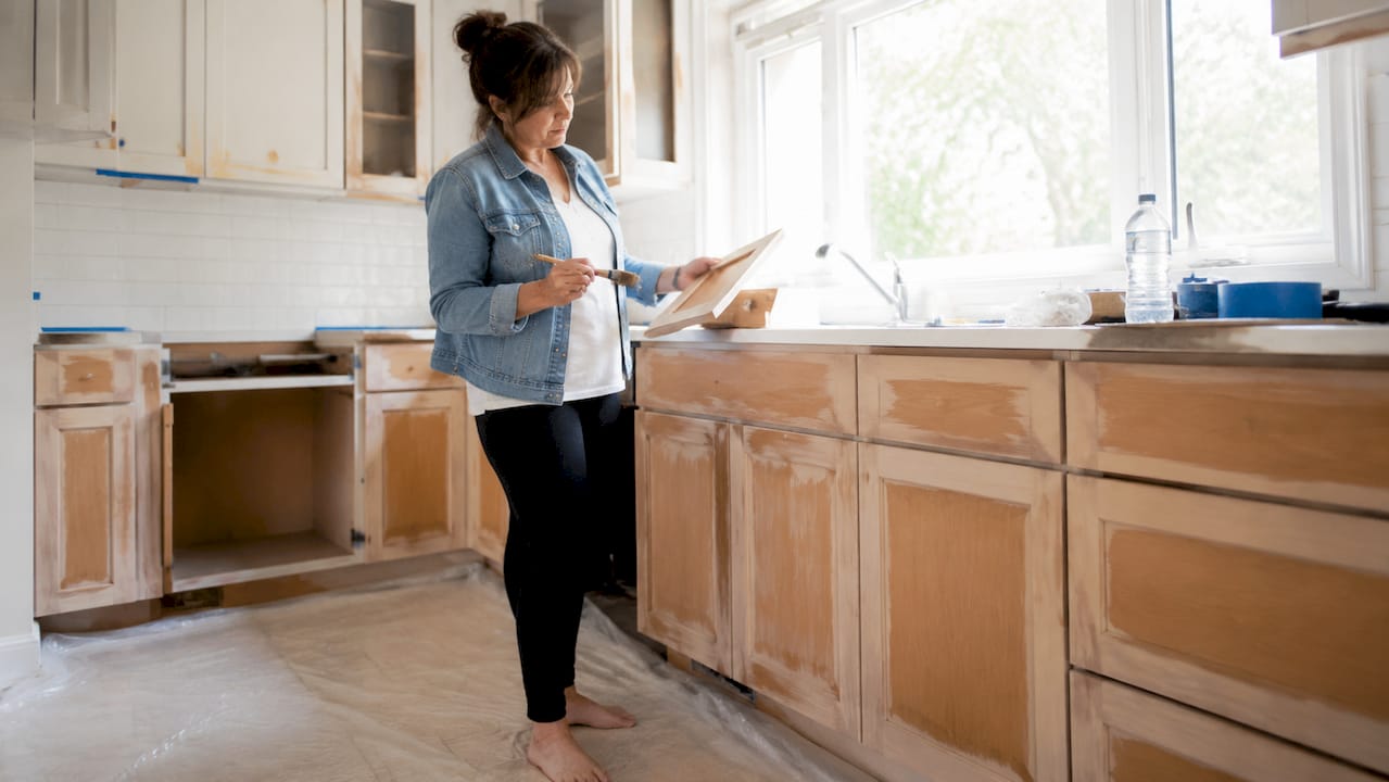 Ottawa homeowner inspecting refinishing kitchen cabinets
