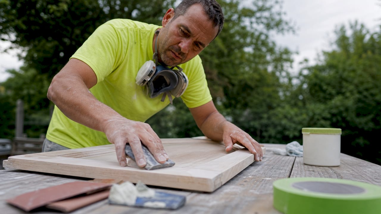 Cabinet painter sanding doors in workshop