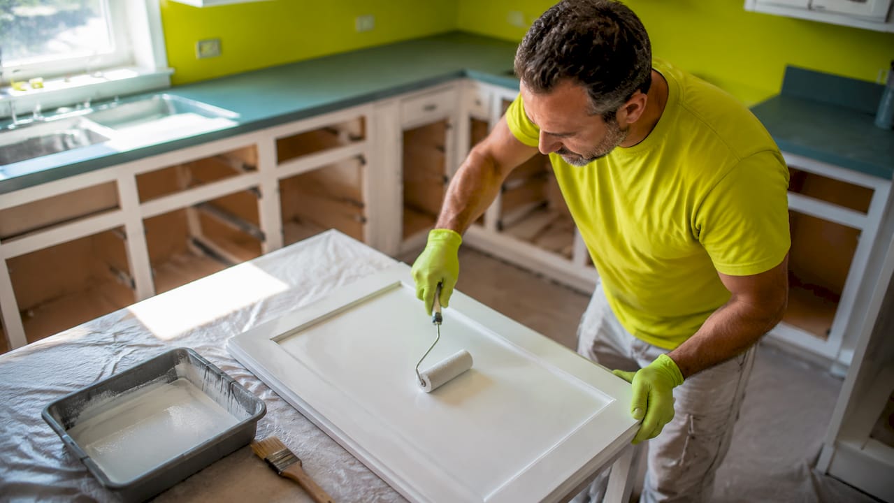 Painter sanding cabinet door in Ottawa kitchen