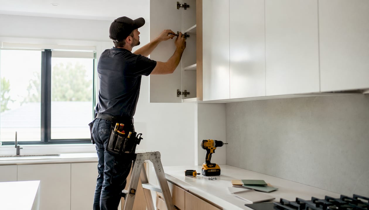 Installer adjusting tall kitchen cabinet door