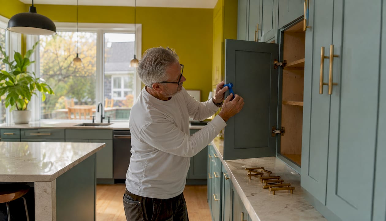 Man carefully reassembling kitchen cabinet doors with fresh paint