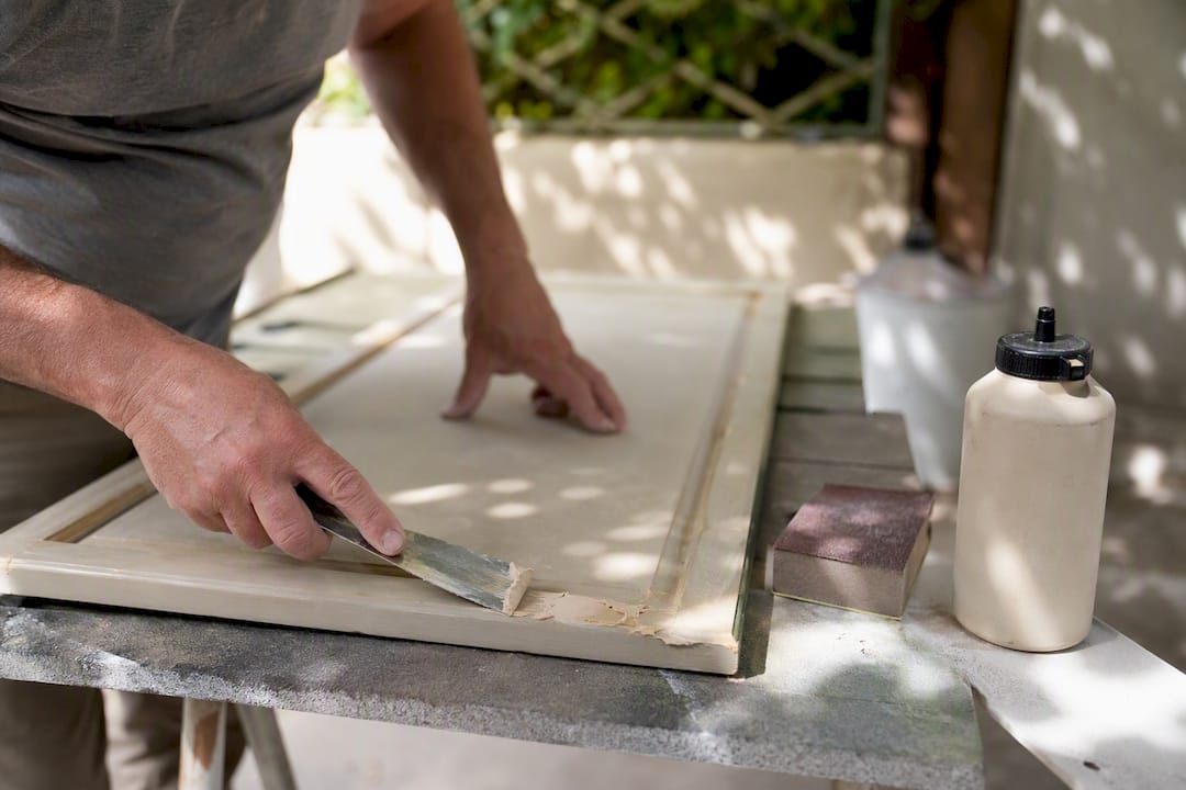 Applying wood filler to cabinet door edge