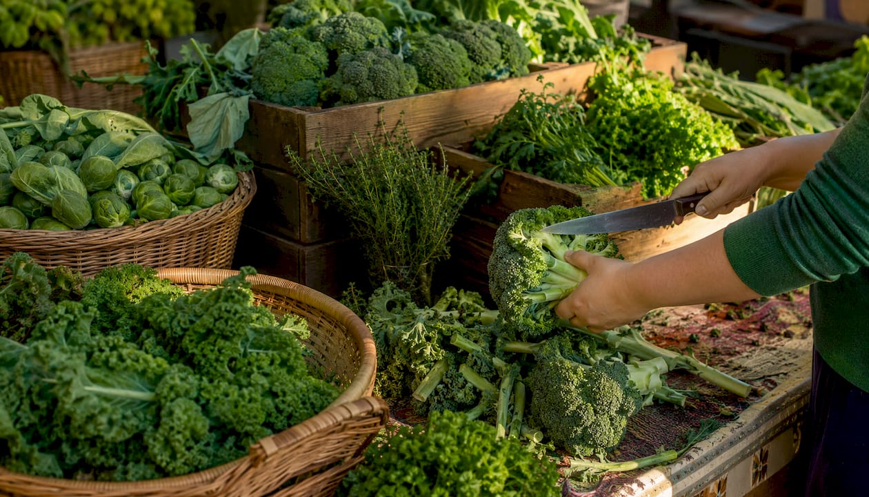Hands chopping cruciferous vegetables on kitchen table