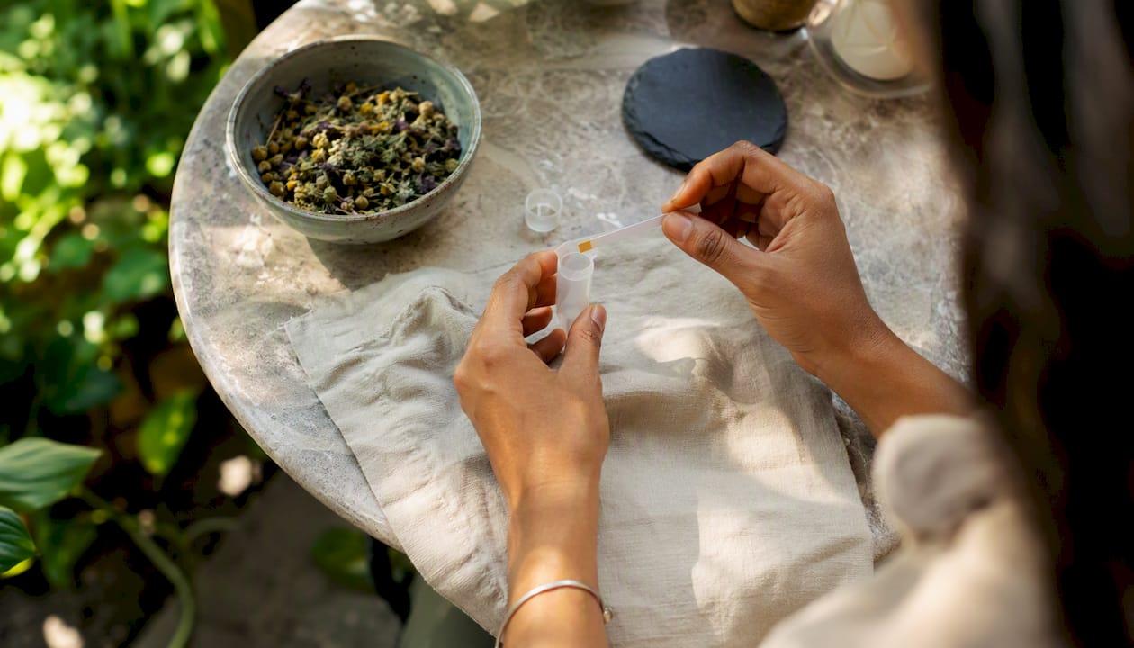 Hands preparing saliva sample with pH test strip