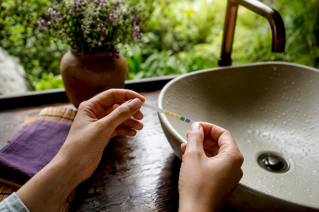 Hands holding urine pH test strip