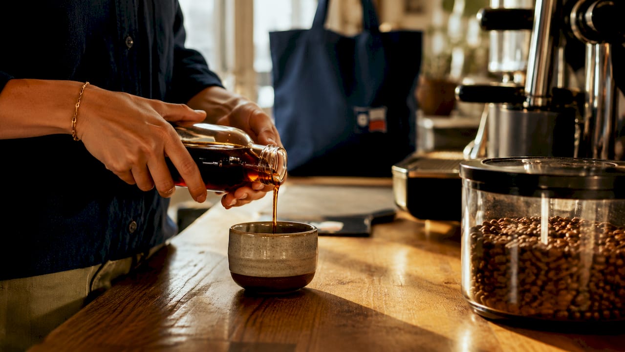 Close-up pouring syrup into espresso cup