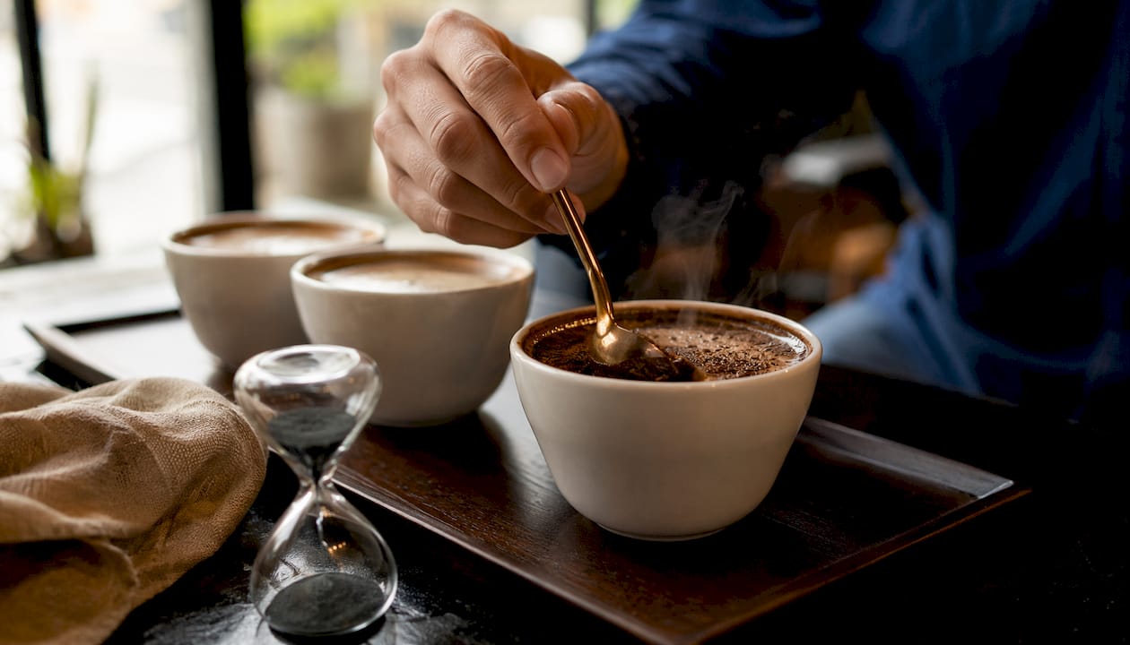 Close-up of hand breaking coffee crust during cupping