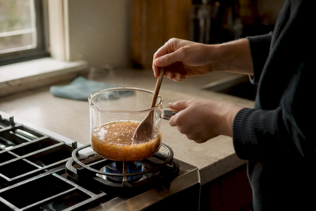 Hands reheating and stirring coffee syrup to fix cloudiness