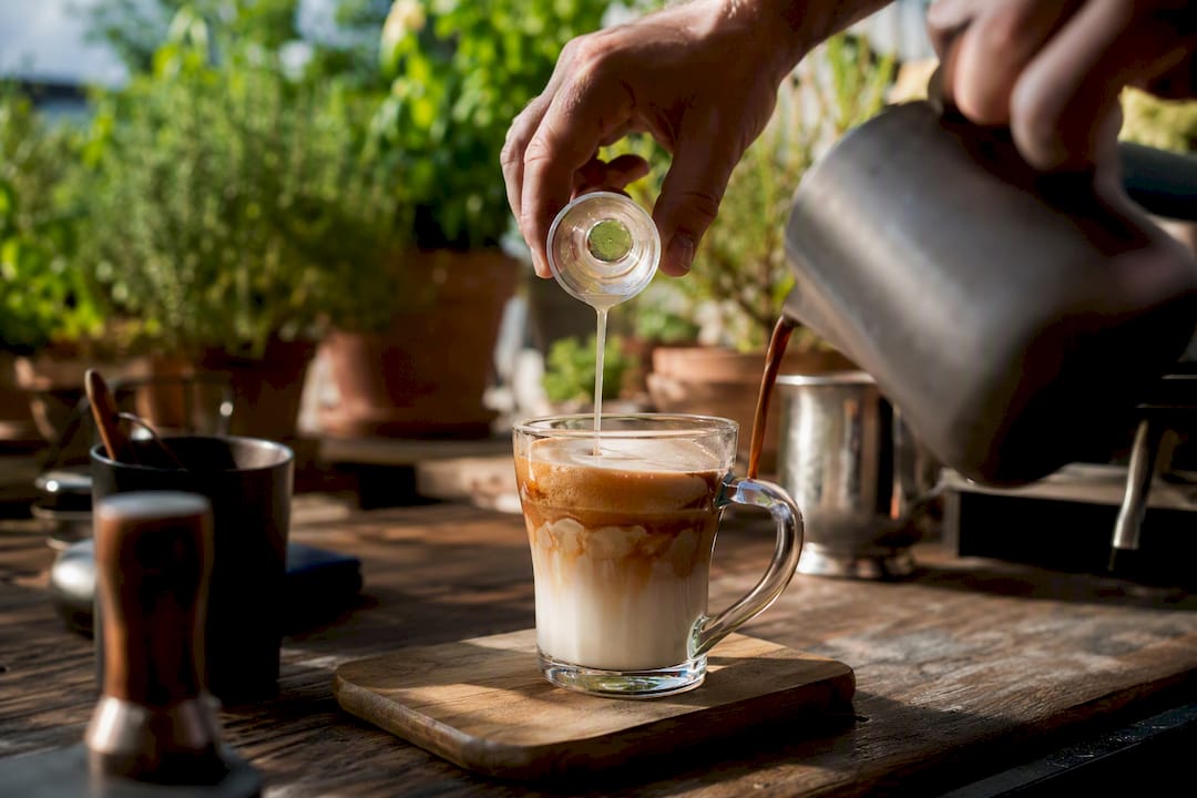 Hands adding syrup to vanilla latte