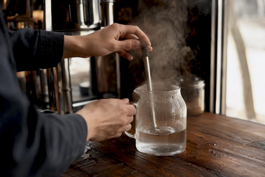 Hands testing espresso machine steam and flow