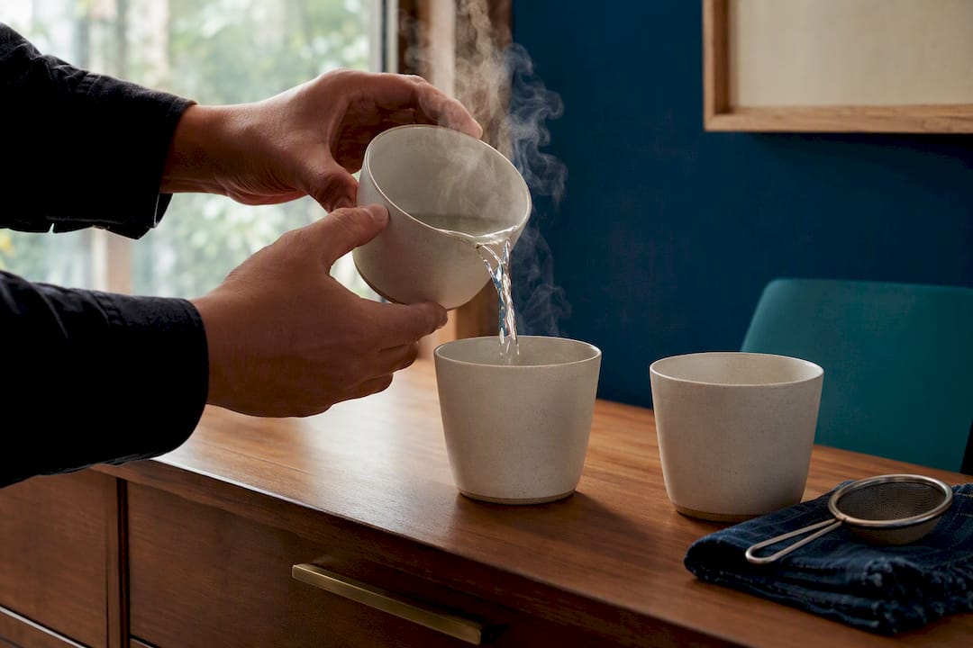 Pouring boiling water between tea cups